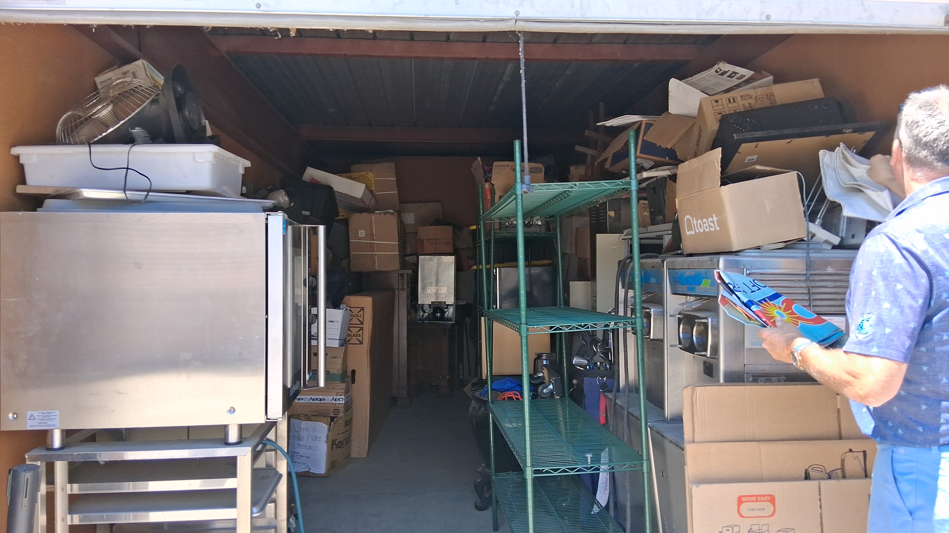 Storage unit packed with commercial kitchen equipment, shelving and boxes before cleanout