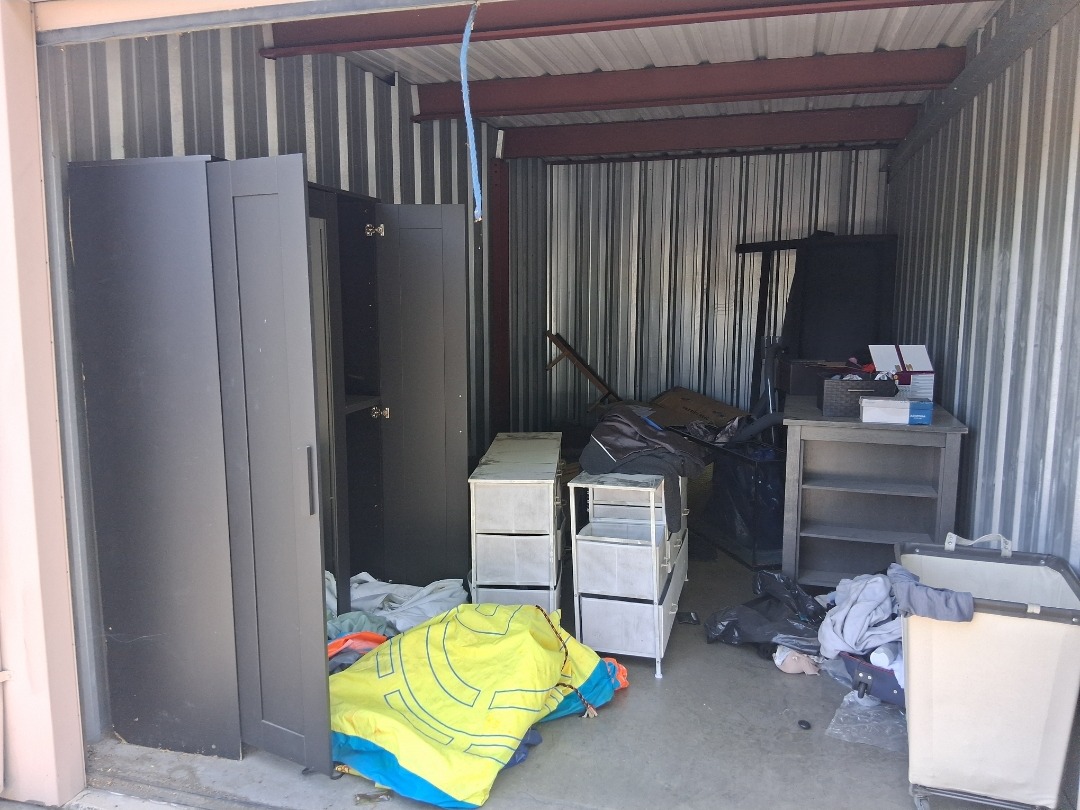 Garage storage unit packed with wardrobes, dressers and tarps before cleanout