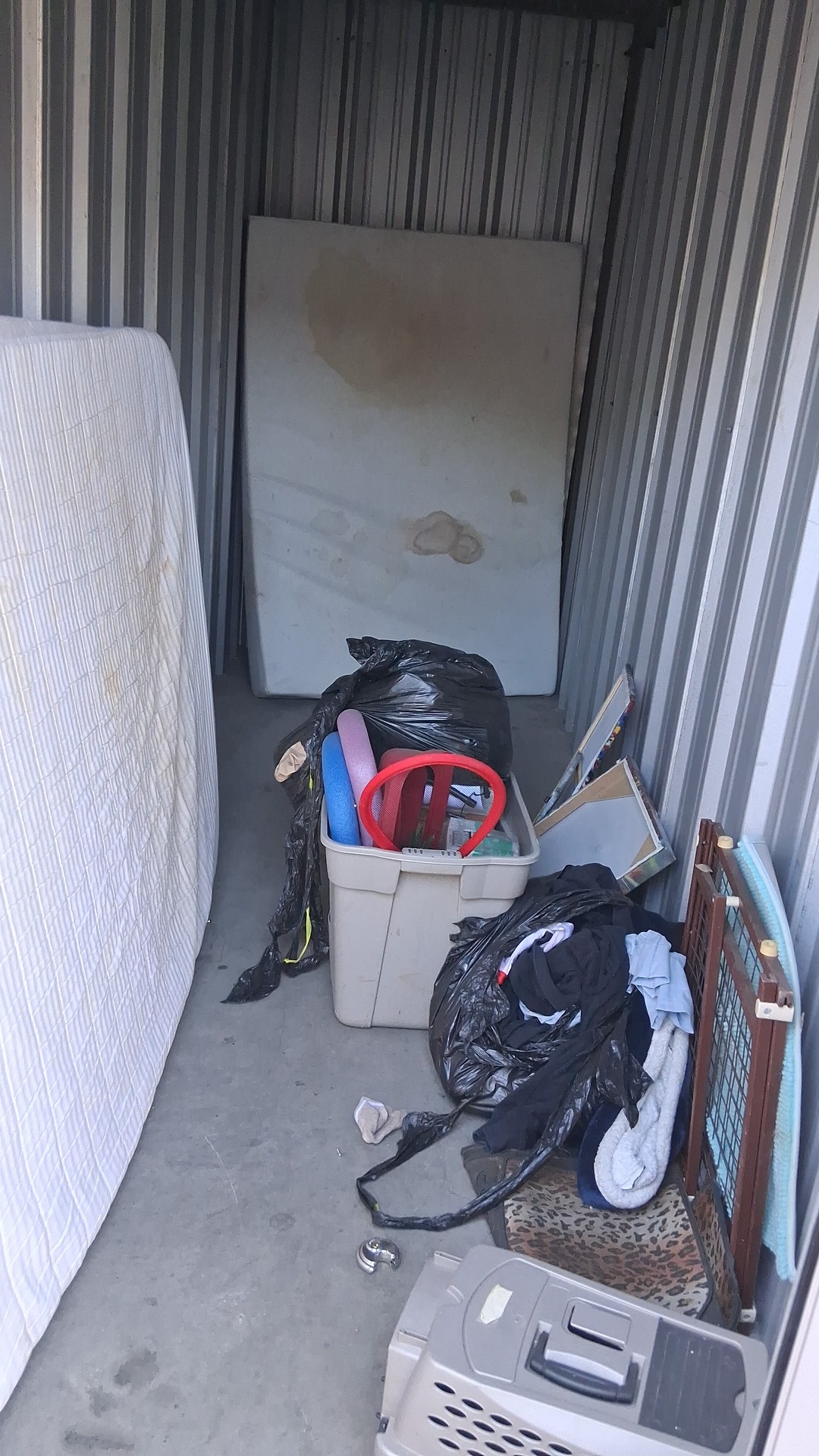 Storage unit with a leftover mattress, bins and bags before final cleanout