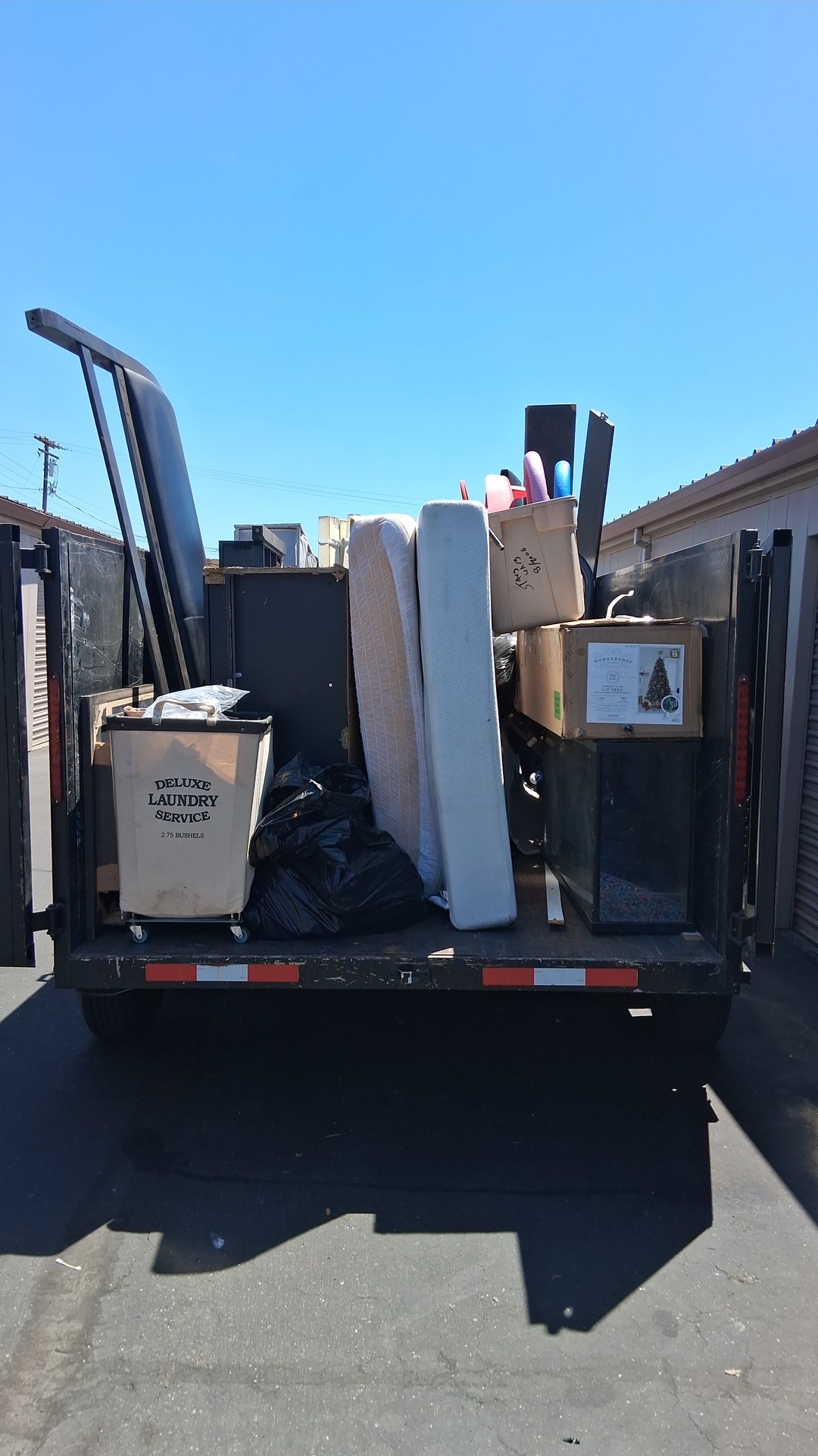 Pro Junk Removal Solutions trailer loaded with a mattress, laundry cart, cabinet and boxes after a job